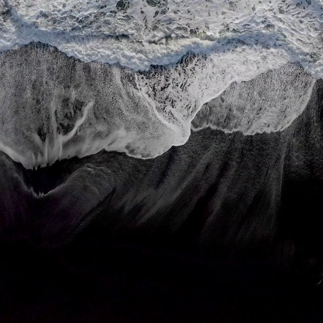 black volcanic sand beach with white sea foam