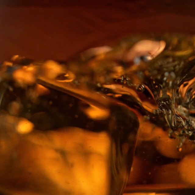 close up of dark liquor and ice in a glass