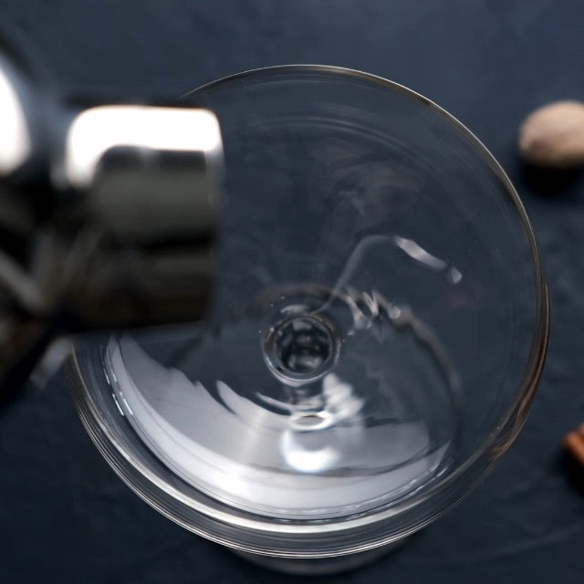 Two glasses of egg nog cocktail with a cinnamon stick on a blurred background