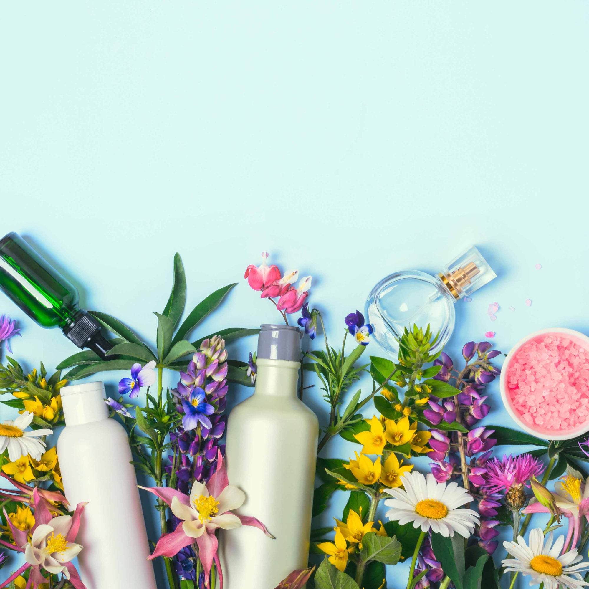 personal care products with fresh flowers on blue background